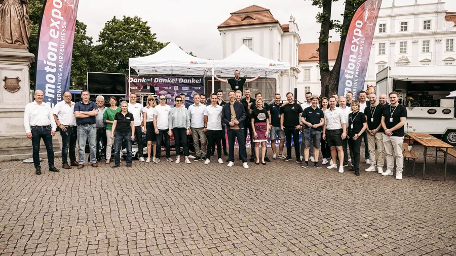 Gruppenbild des Messeteams vor dem Schloss Oranienburg, links und rechts Fahnen der e-motion expo.