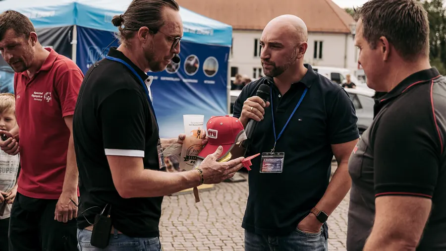 Interview mit Mikrofon an einem Messestand unter freiem Himmel.